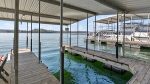 A covered dock area with a view of the water and boats in the background. - Amazing Views Close to the Strip - Private Dock! (Lake Ozark)