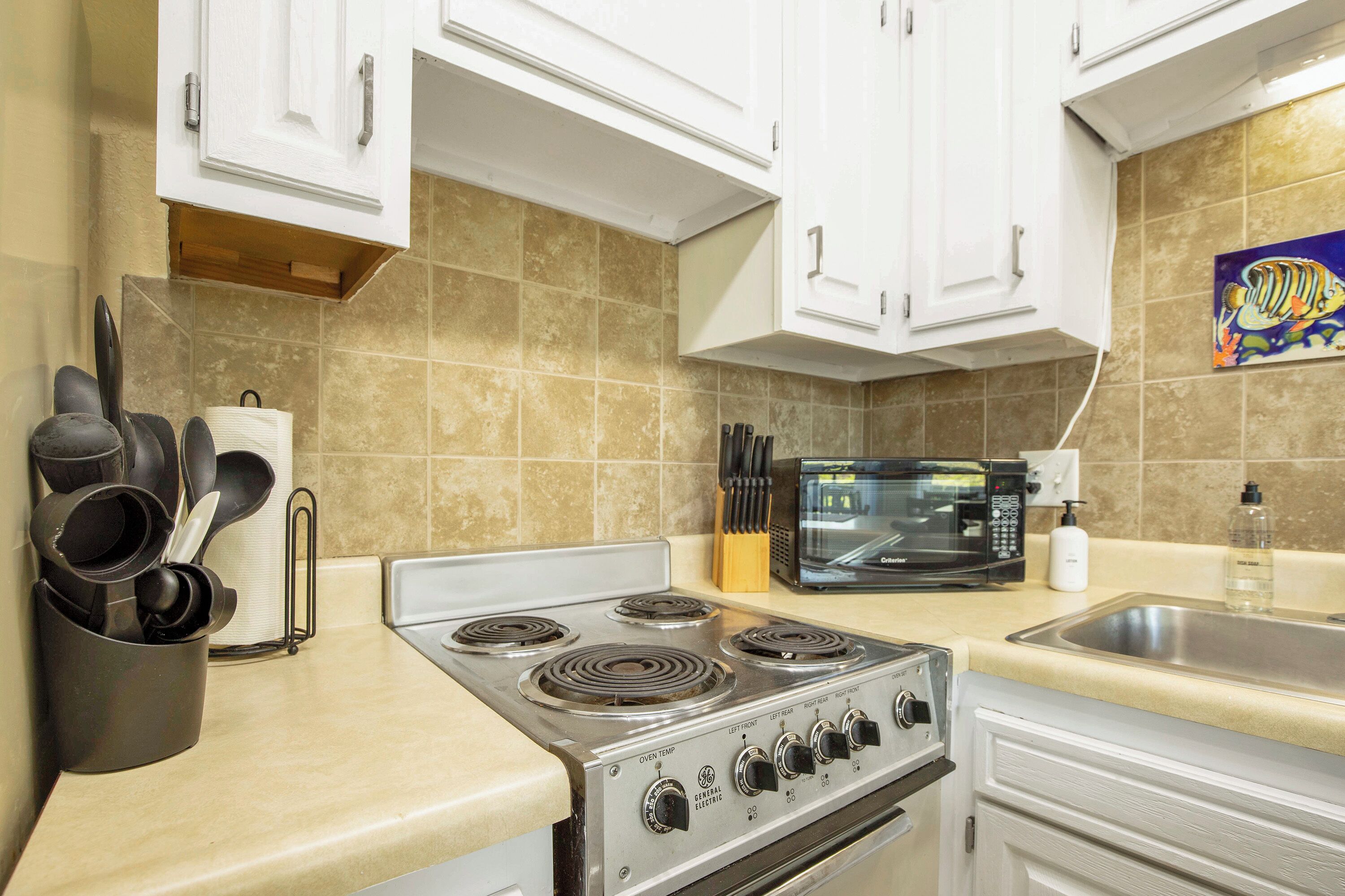 A kitchen with a stove, microwave, and sink.