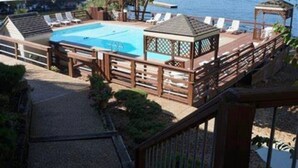 Un espace piscine doté d’une terrasse en bois, de chaises longues et d’un gazebo.