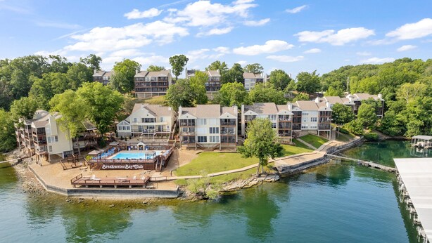 Un quartier résidentiel au bord du lac, composé de plusieurs maisons à deux étages, d’une piscine et d’un quai.