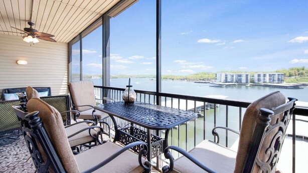 Un balcon avec une table et des chaises, donnant sur une étendue d’eau et des bâtiments.
