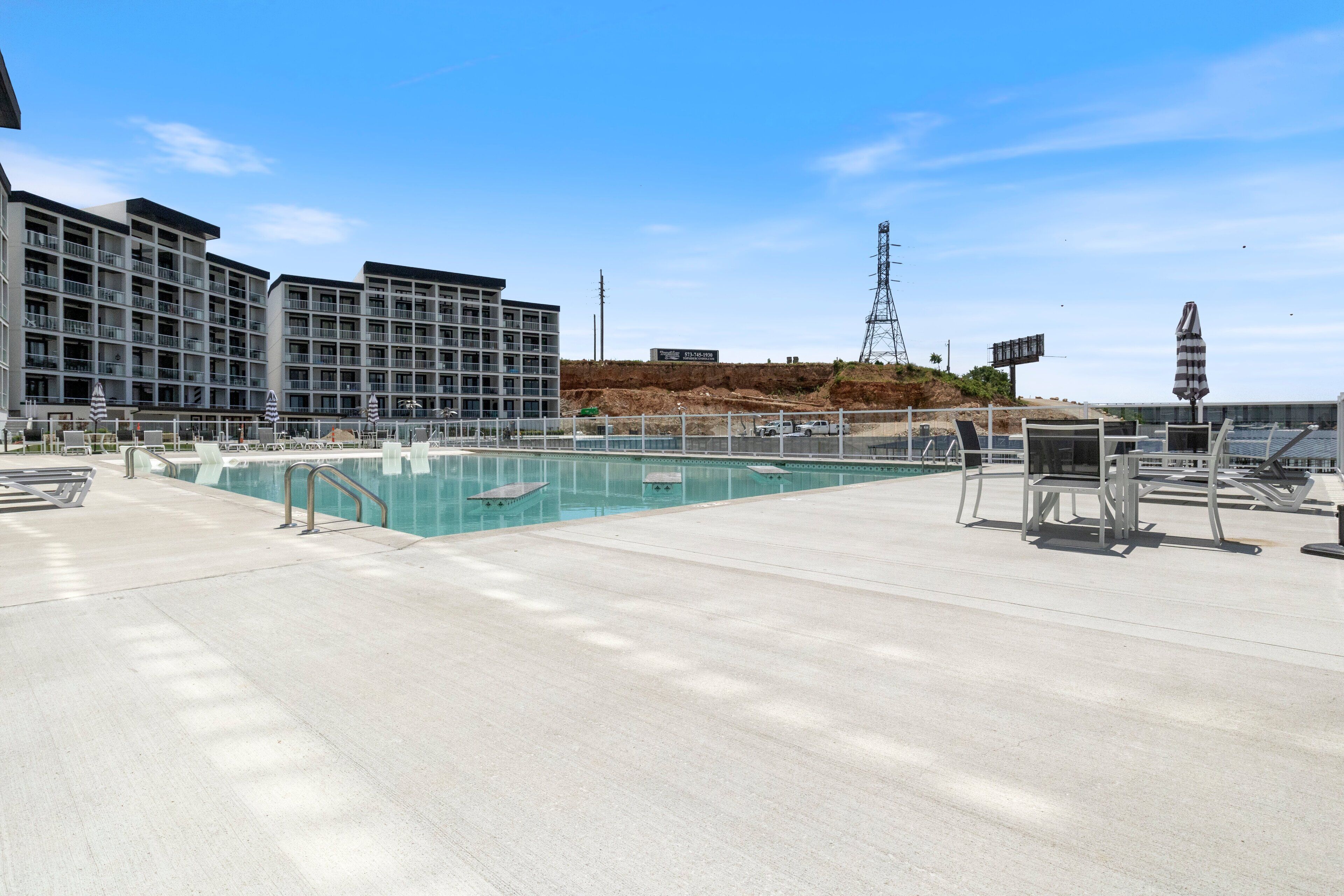 Ein Poolbereich mit Blick auf ein Hotelgebäude und eine Baustelle im Hintergrund.