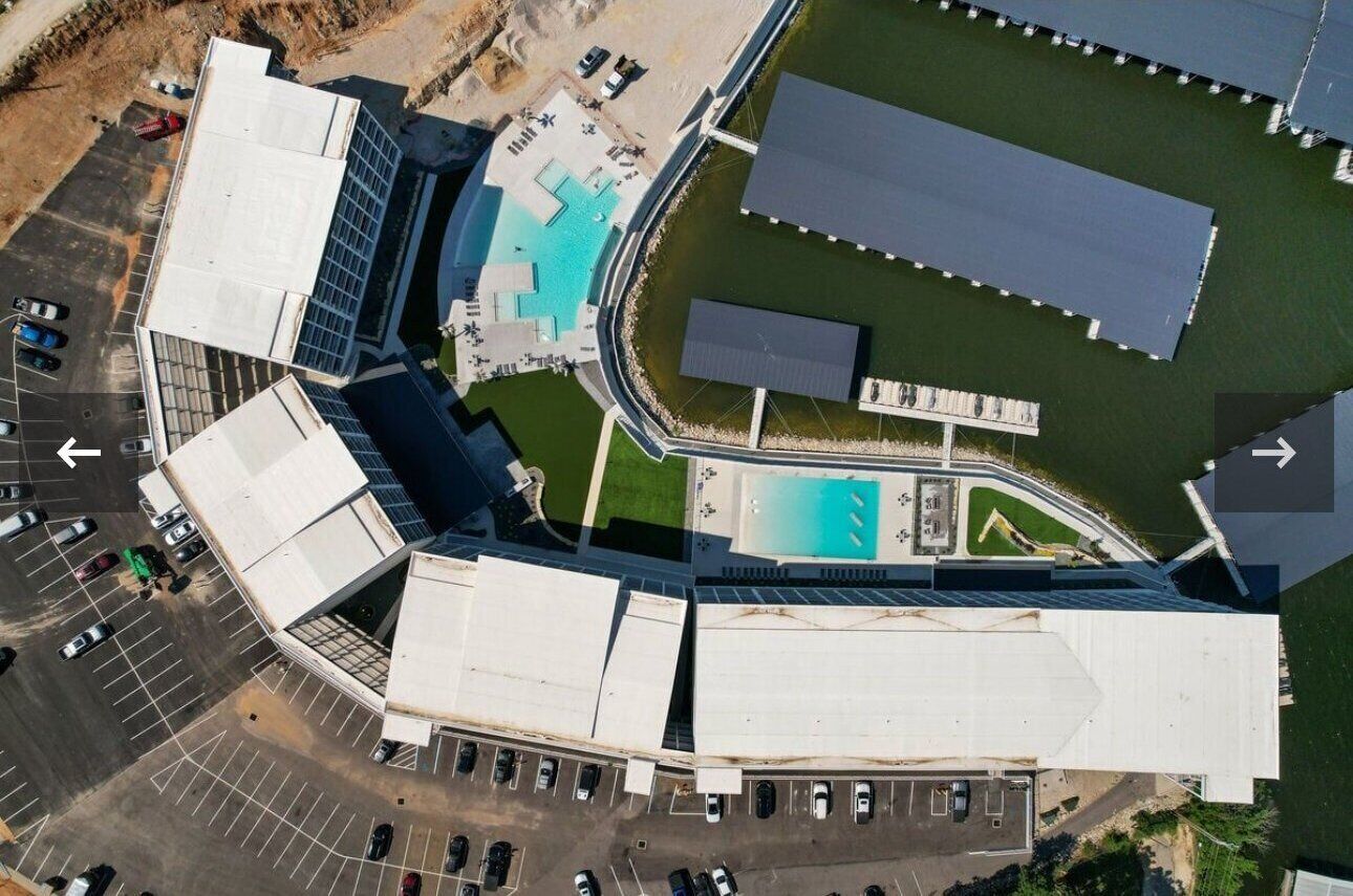 Vue aérienne d’un bâtiment moderne doté d’une piscine, d’un parking et d’un espace vert.