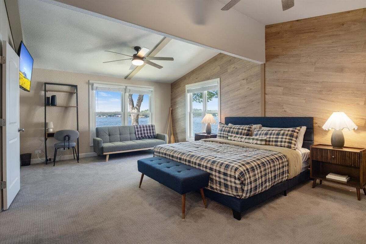 Een slaapkamer met een groot bed, een bureau, een stoel en uitzicht op het groen.