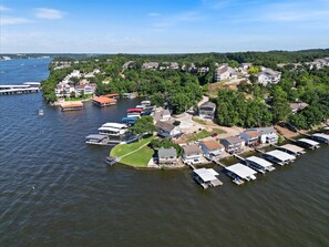 Vue aérienne d’un quartier résidentiel au bord d’un lac, avec des maisons, des quais et des bateaux.