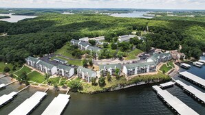 Vue aérienne d’un complexe hôtelier comprenant plusieurs bâtiments, une zone de quai et un lac en arrière-plan.
