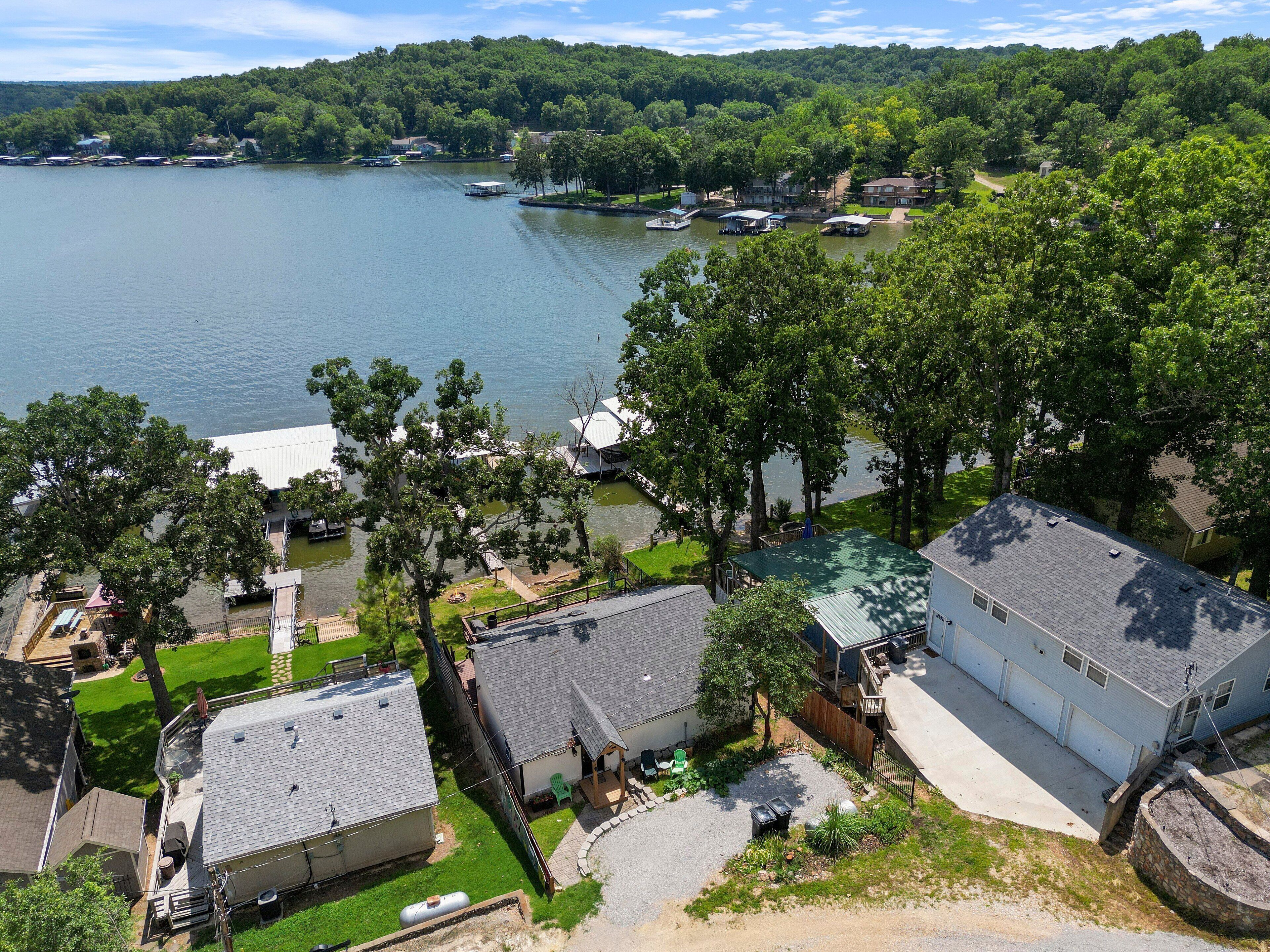 A lakeside property with multiple boats, a dock, and a house with a large garage.