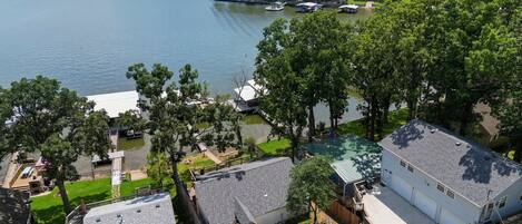 A lakeside property with multiple boats, a dock, and a house with a large garage.