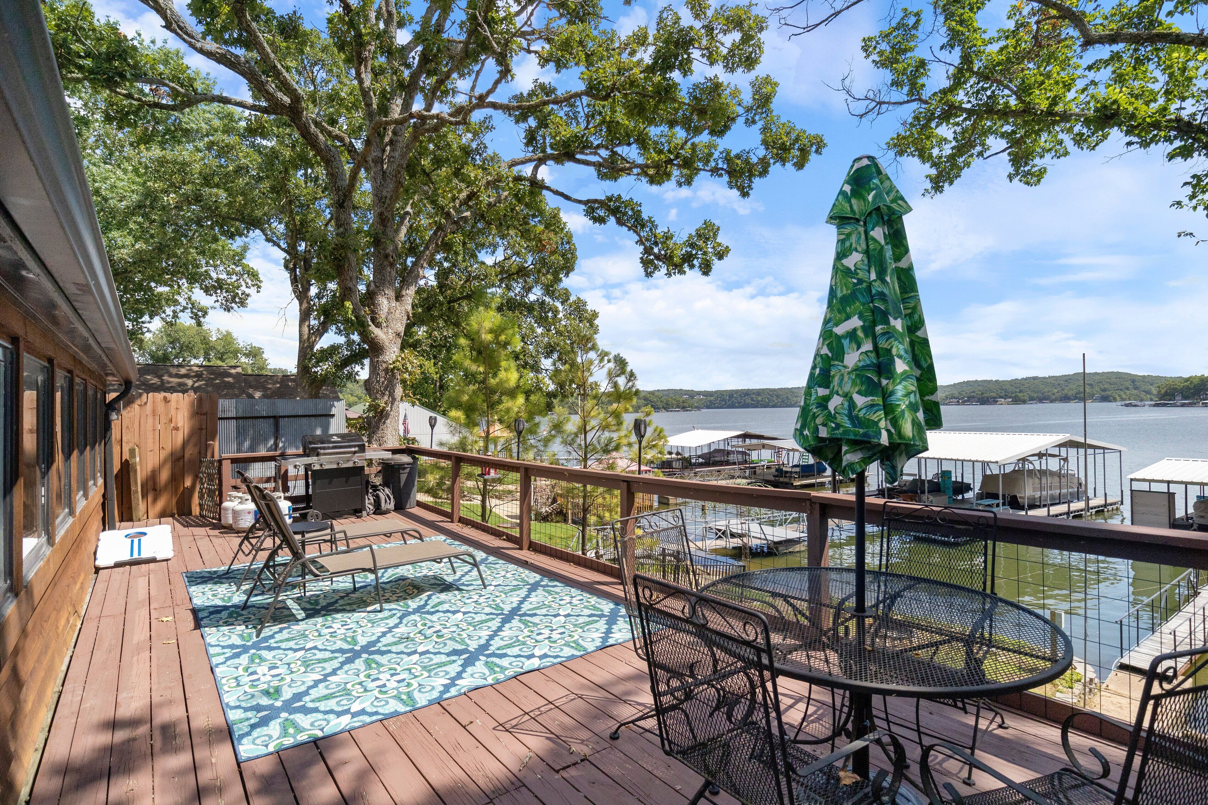A wooden deck with a pool table, outdoor seating, and a view of a lake.