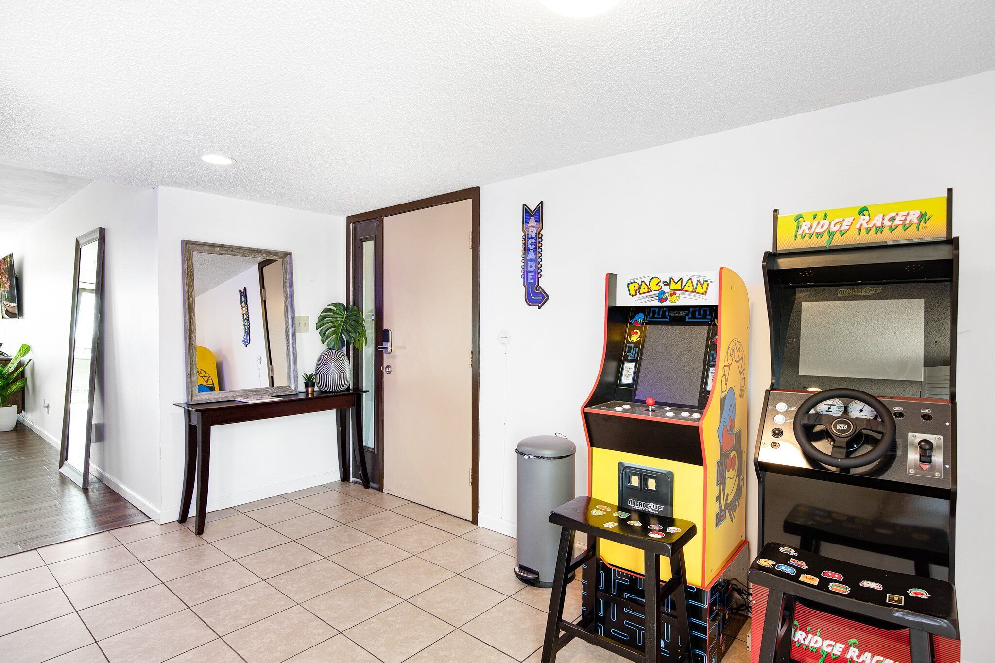 Un couloir avec des bornes d’arcade, une poubelle et une porte.
