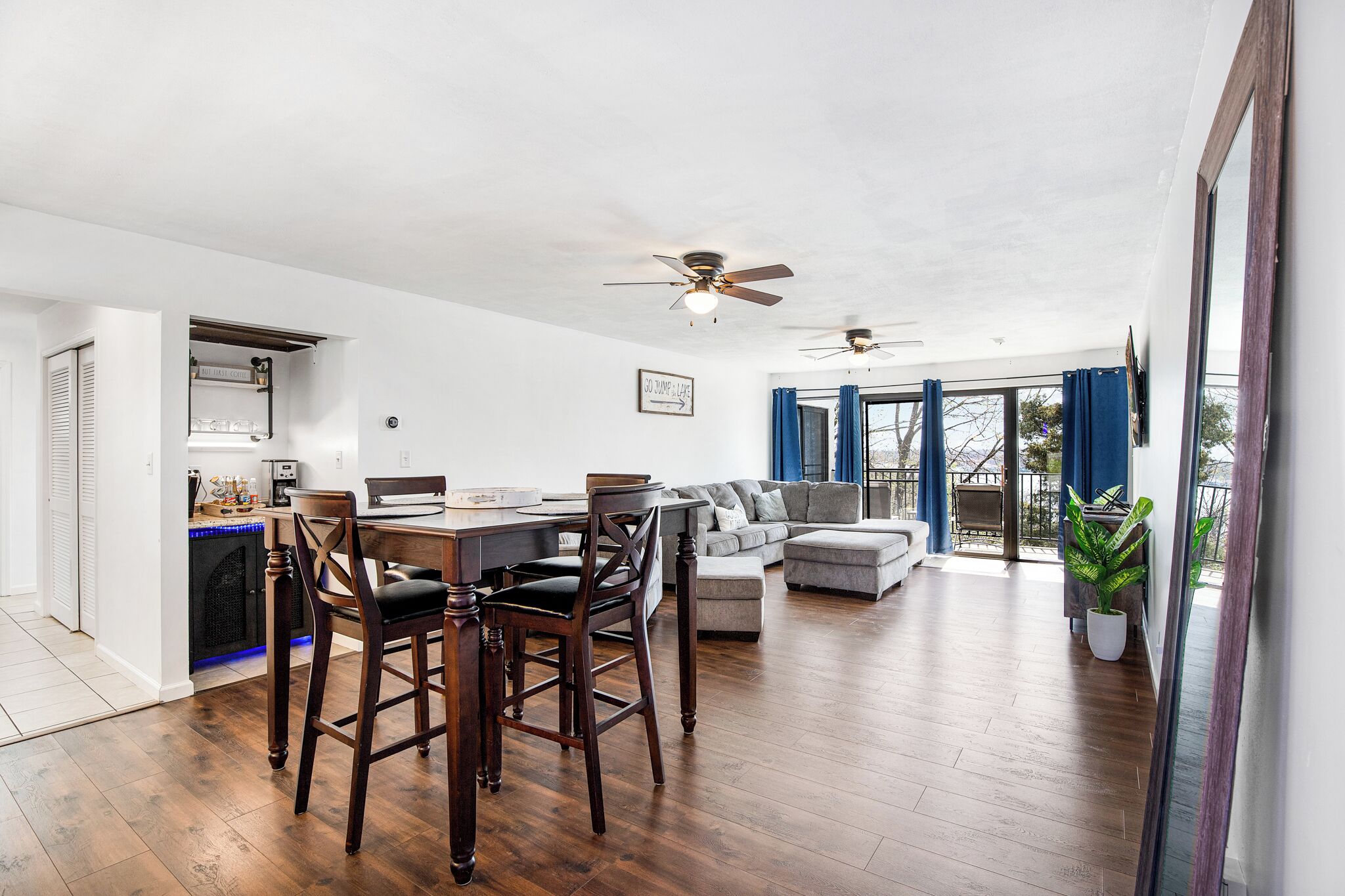 Ampla sala de estar com mesa de jantar, cadeiras, sofá e ventilador de teto.