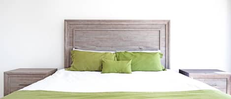 A bed with a wooden headboard, two green pillows, and a green blanket.