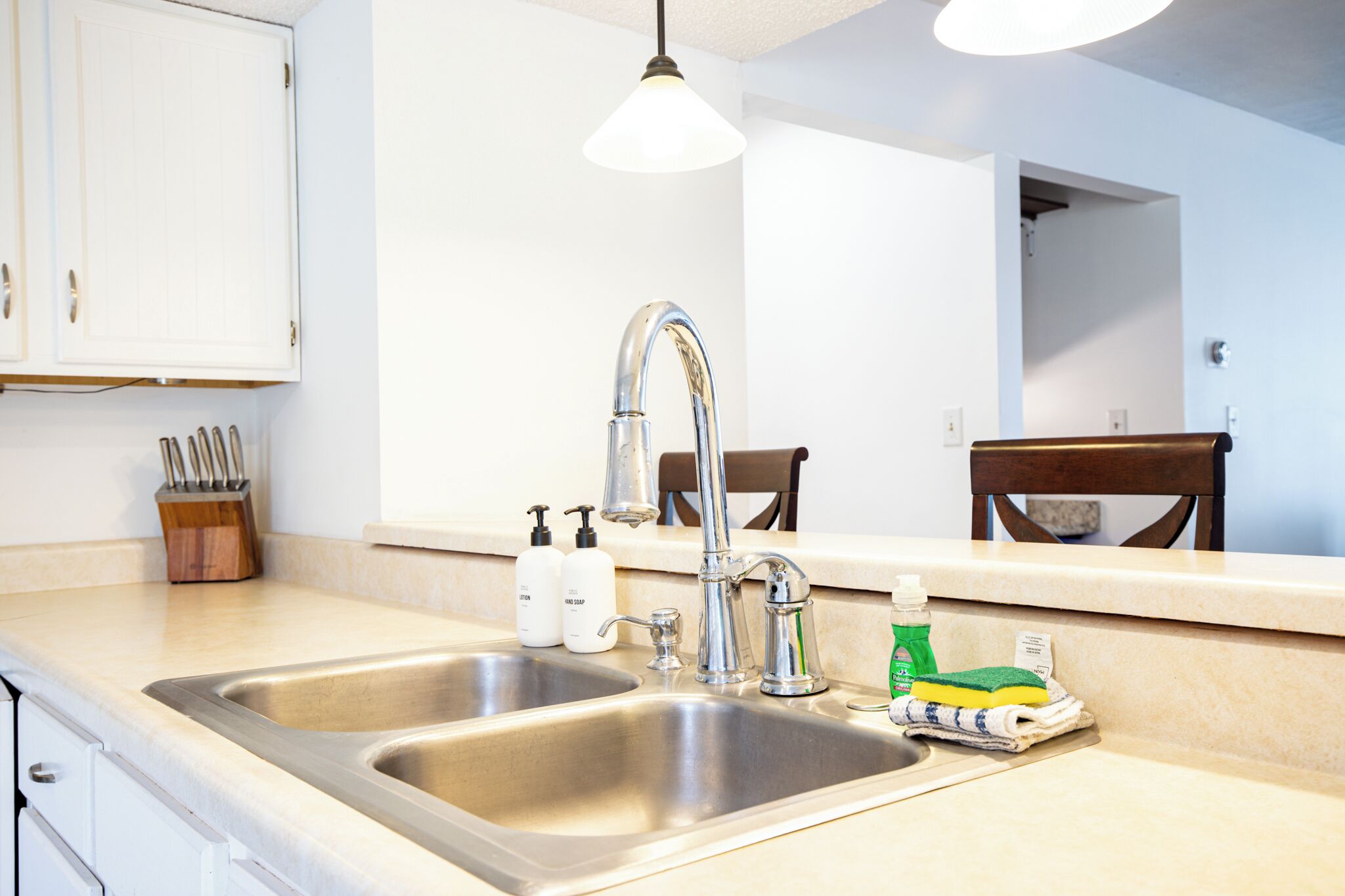 A kitchen with two stainless steel sinks, a wooden knife block, and a mirror above the countertop.