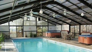 An indoor swimming pool with a covered roof, ceiling fans, and seating areas. - Treetop Vibes on Horseshoe Bend (Lake Ozark)