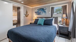A bedroom with a large bed, a wooden ceiling, a painting on the wall, and a window with curtains. - Lakefront Fishing Retreat w/ Dock, Hot Tub & Deck Views (Sunrise Beach)