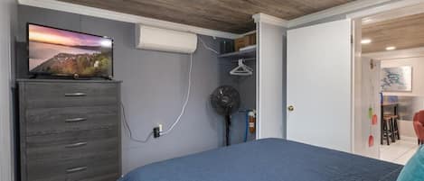 A bedroom with a bed, a dresser, a TV, and a fan.