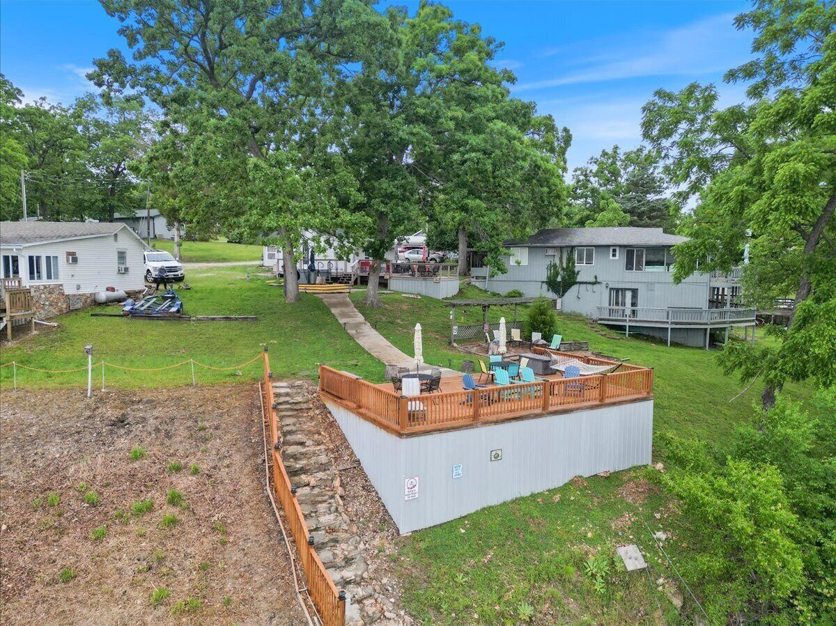 A backyard with a wooden deck, outdoor furniture, and a swimming pool.