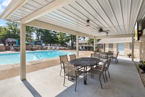 A covered outdoor area with a pool, patio furniture, and a stone building in the background. - Central Location, Unlimited Indoor & Outdoor Fun (Osage Beach)