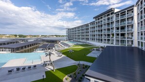 A modern hotel with a large pool, multiple balconies, and a well-maintained lawn. - Scenic Views, Outdoor Grill & Dine, Fireplace, Games (Osage Beach)