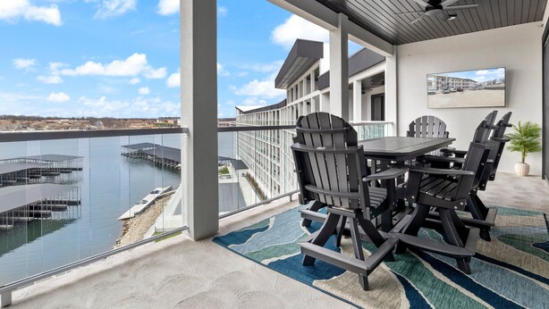 A covered outdoor area with a view of a marina, a dining table with chairs, and a ceiling fan. - Scenic Views, Outdoor Grill & Dine, Fireplace, Games (Osage Beach)