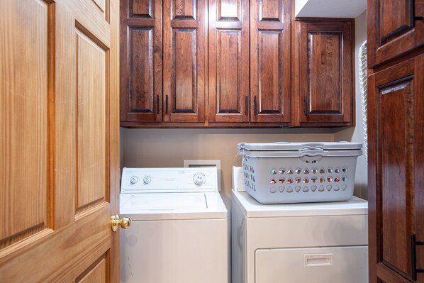 A laundry area with wooden cabinets and a stacked washer and dryer.