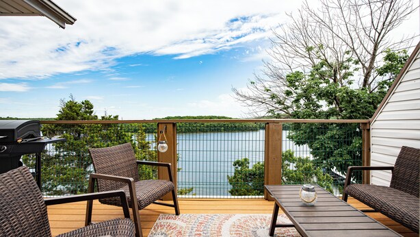 Una terrazza con mobili in vimini, un barbecue e vista su un lago.