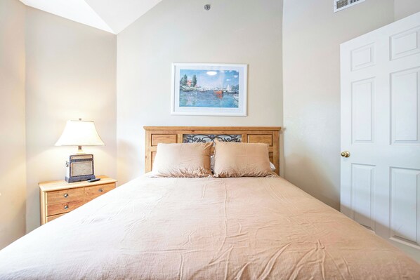A neatly made bed with a headboard, a bedside table with a lamp, and a framed picture on the wall. - Amazing Views From Balcony, Loft & Gated Pool (Kaiser)