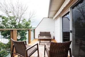 A balcony with wicker furniture, a table, and a view of a tree and a building. - Amazing Views From Balcony, Loft & Gated Pool (Kaiser)