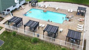Una piscina con lettini e ombrelloni, circondata da una terrazza con recinzione.