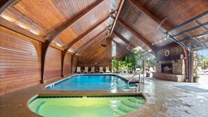 Una piscina interior amb sostre de fusta i una llar de pedra.