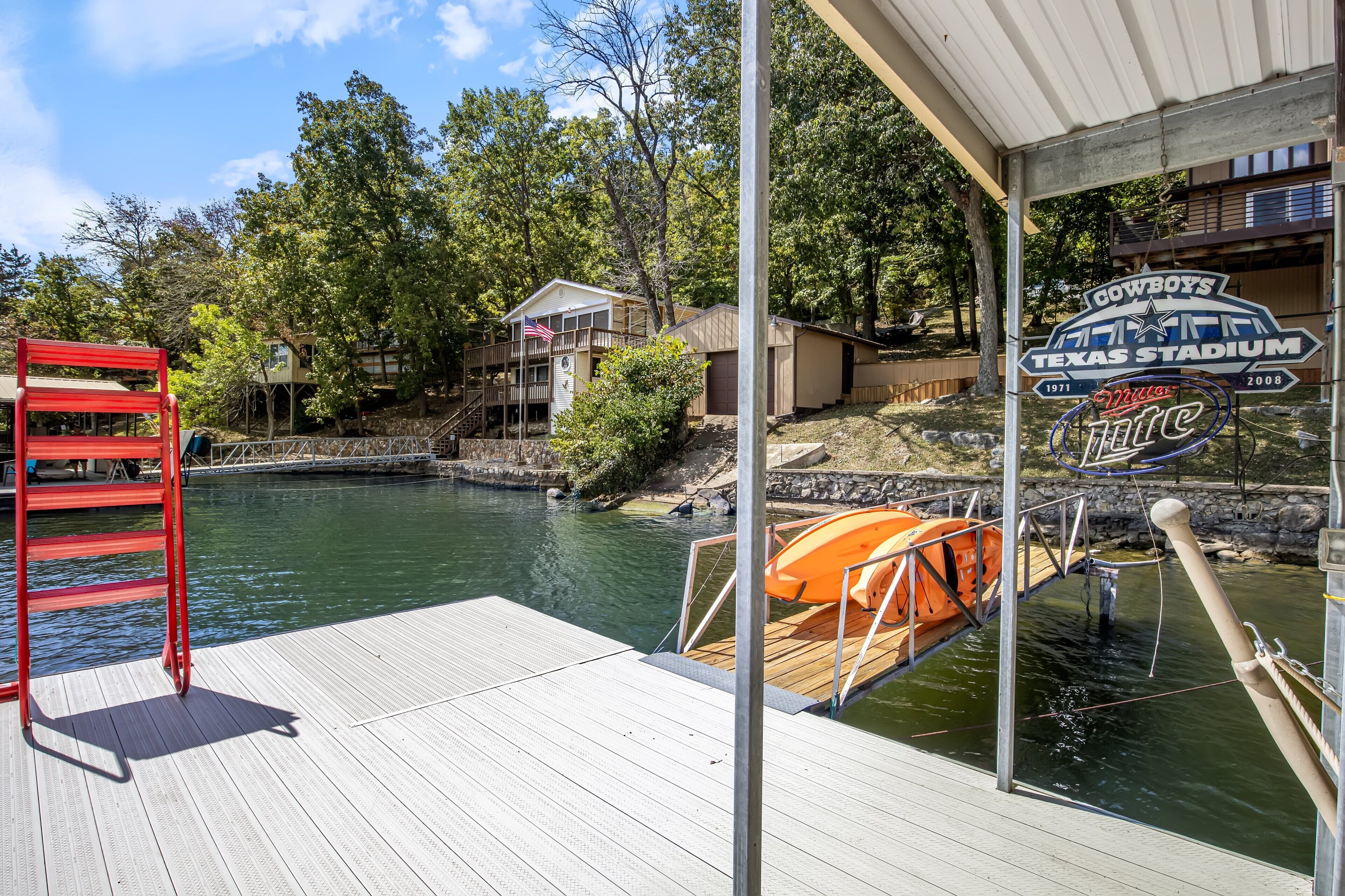 A wooden deck with a red ladder, a boat docked in a body of water, and a sign for Cowboys Texas Stadium.