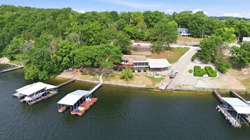 Una propiedad frente al lago con muelle, casa y césped bien cuidado.