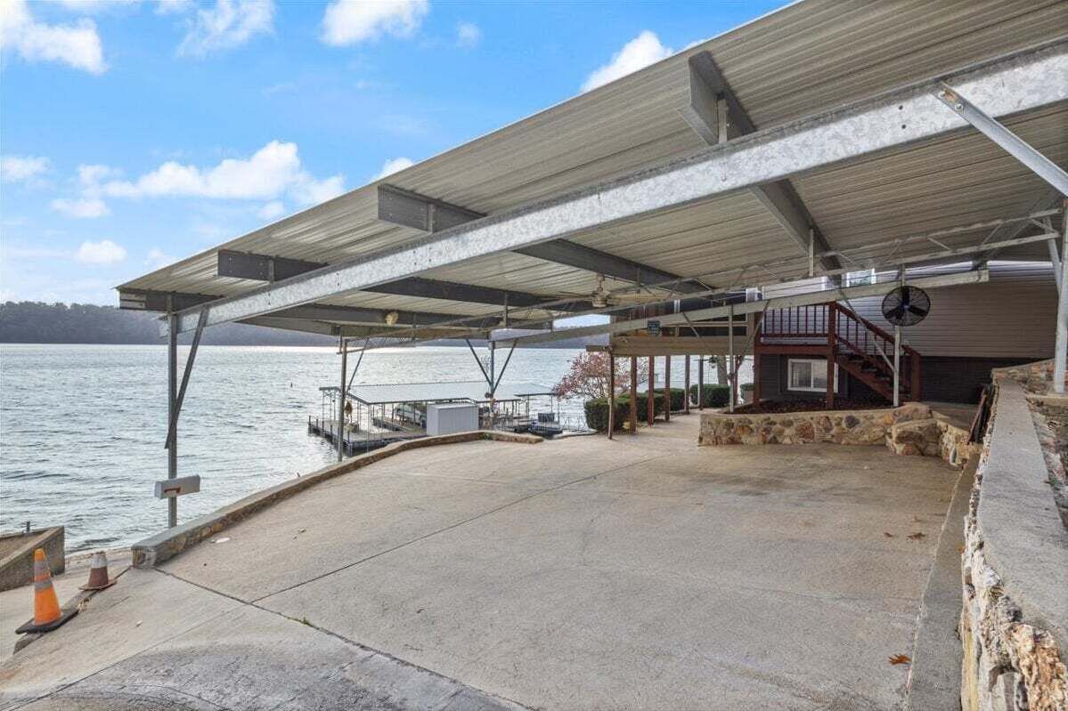 Un edificio frente al agua con un paseo techado, un muelle y un pequeño edificio con escaleras.