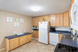 Una cocina con armarios de madera, un refrigerador blanco, un lavavajillas y una estufa a gas.