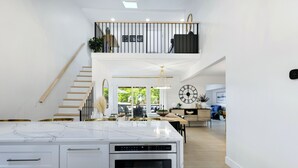 A modern kitchen with a large island, a built-in oven, and a staircase leading to an upper level. - Newly Remodeled w/ Dock, Boat & PWC Slips, Pool Table & Golden Tee (Osage Beach)