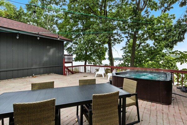 Une terrasse extérieure avec un jacuzzi, des fauteuils en osier et une table.