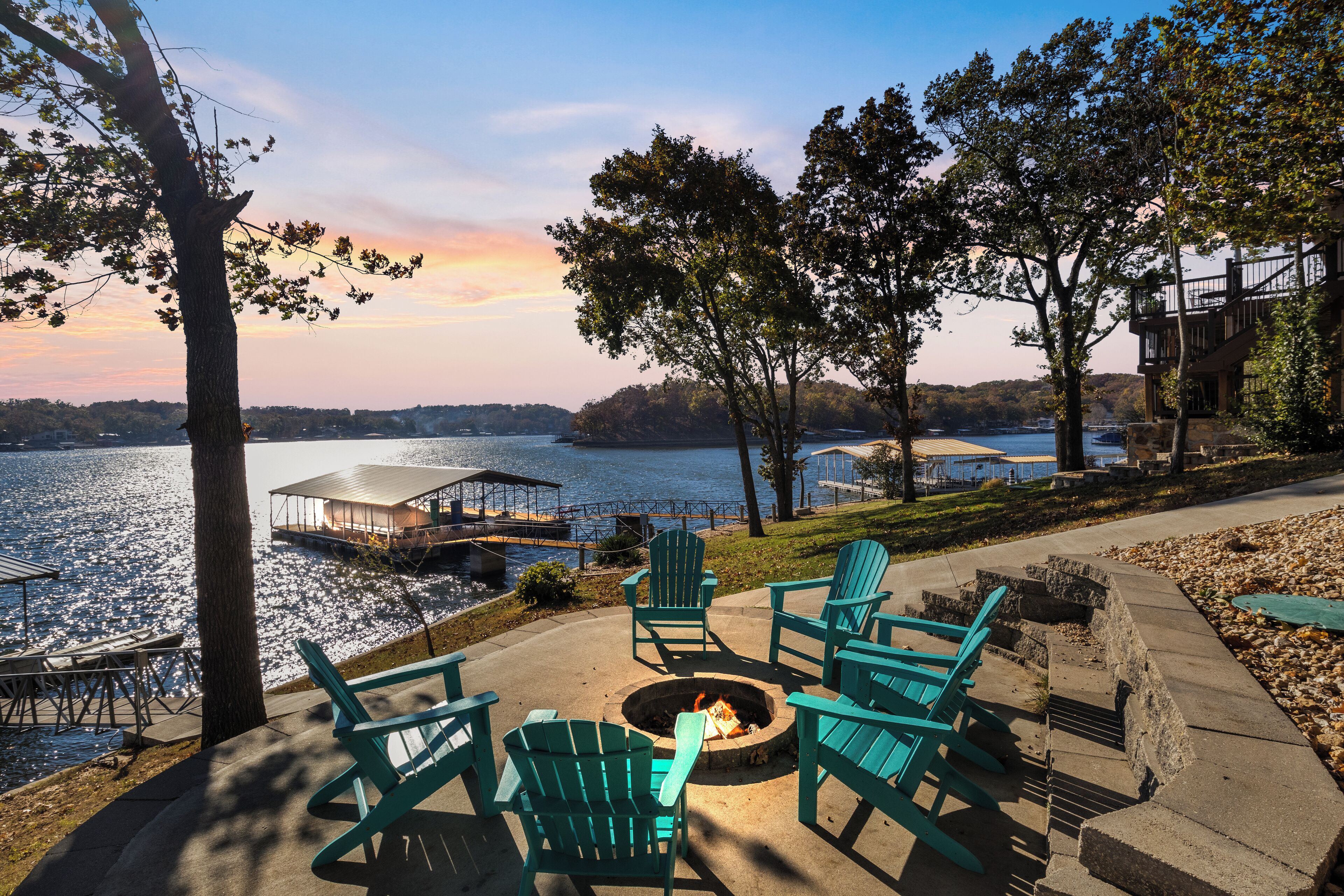 Una terrazza sul lago con poltrone Adirondack, un braciere e vista sul lago e sul pontile.