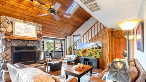 A cozy living room with a stone fireplace, leather sofas, a coffee table, and a television.
