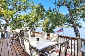 Eine Holzterrasse mit Gartenmöbeln, mit Blick auf ein Gewässer mit einer amerikanischen Flagge.