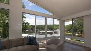 A spacious room with large windows offering a view of a lake and dock area. - Great Location & Lake Views, Boat Slip (Lake Ozark)