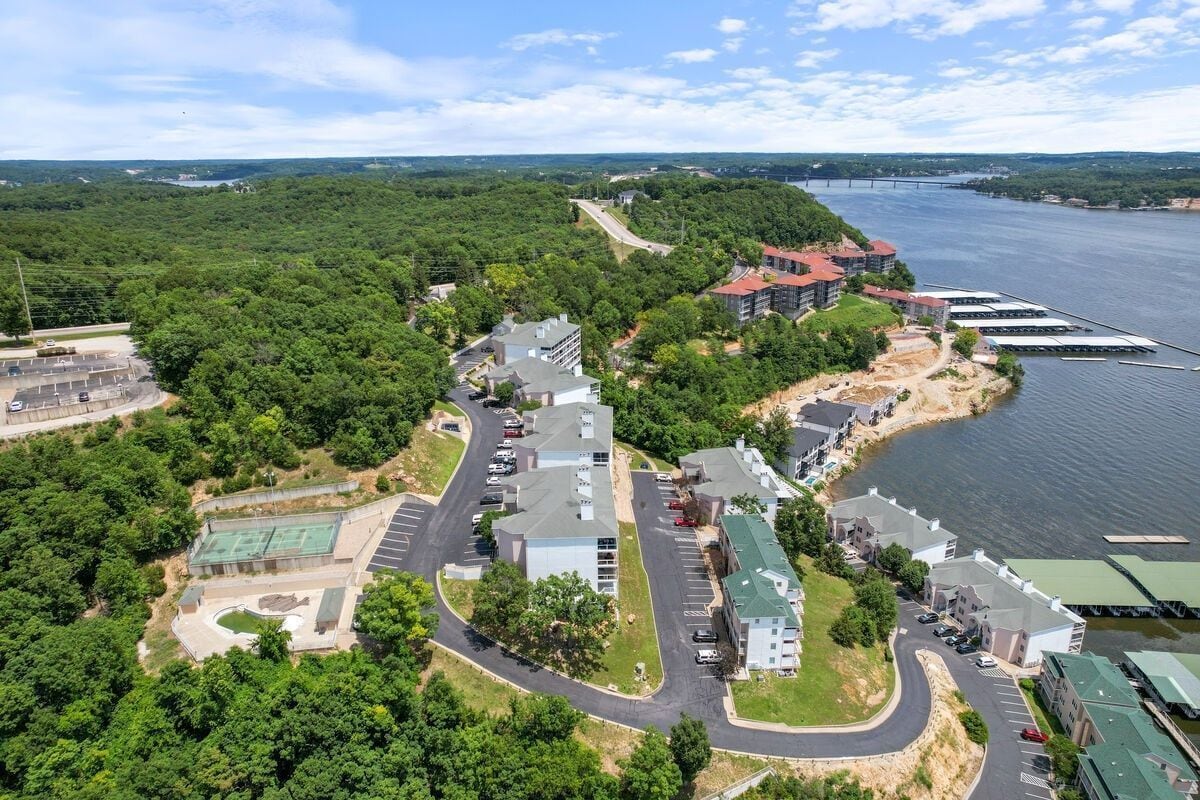An aerial view of a residential area with a river, a bridge, and a mix of modern and traditional buildings.