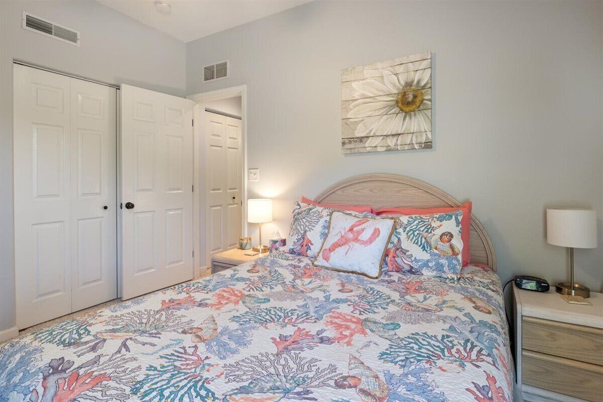 A bedroom with a bed, nightstands, a wall clock, and a door.