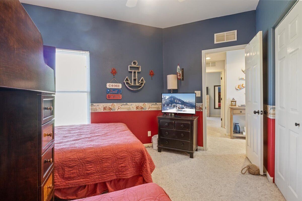 Une chambre avec deux lits, une commode, un téléviseur et des éléments de décoration murale sur le thème de la marine.
