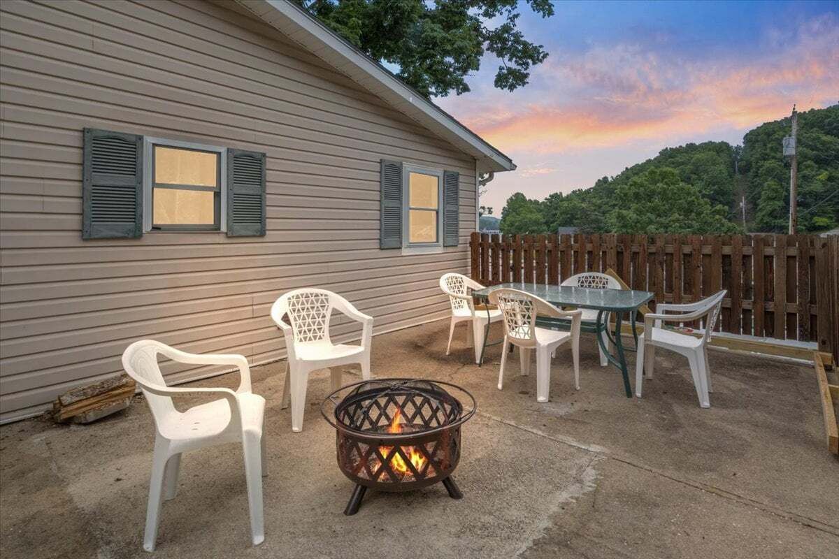 A house with a fire pit, outdoor furniture, and a wooden fence.