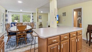 A spacious kitchen with a large island, wooden cabinets, and a dining area with chairs and a table. - Lakefront Escape, Sunrise Views, Boat Slip & Community Dock Access (Roach)
