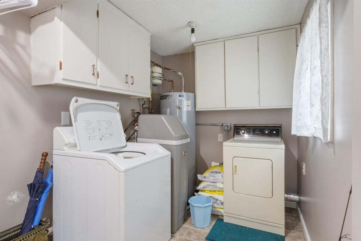 Une petite buanderie équipée d’un lave-linge, d’un sèche-linge et d’un chauffe-eau.
