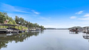A calm lake with docked boats and a covered area on the left. - Lakefront Escape, Sunrise Views, Boat Slip & Community Dock Access (Roach)