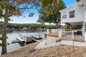 A lakeside property with a dock, a covered deck, and a white building with large windows. - Pet-friendly Home, Great Dock, Waterfront, Lake Views, Boat Slip (Linn Creek)