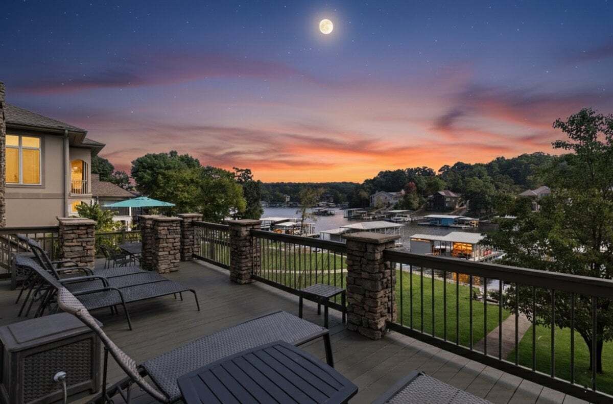 A deck with outdoor seating and a view of a lake at sunset.