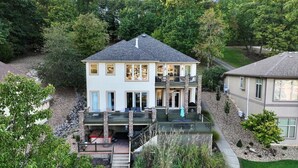 Une maison à deux étages dotée d’un balcon, d’une terrasse couverte et d’un jardin aménagé.